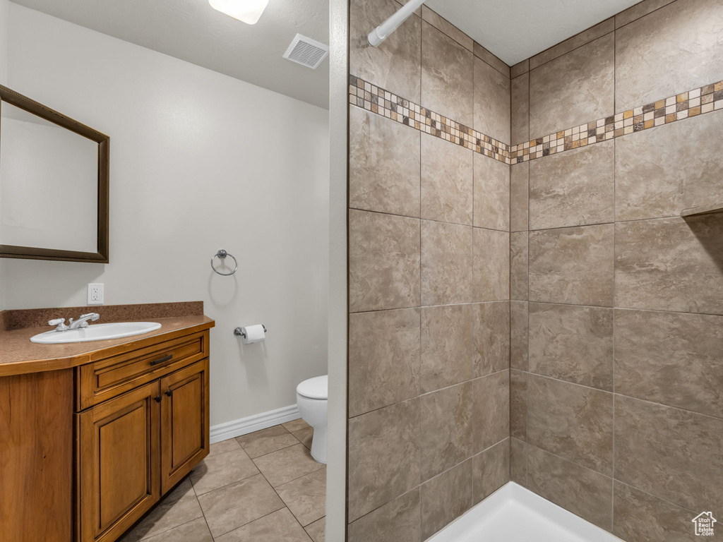 Full bathroom featuring vanity, a tile shower, and tile patterned flooring