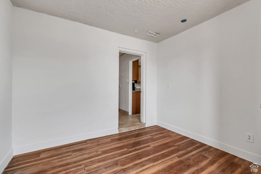 Unfurnished room featuring wood finished floors and a textured ceiling