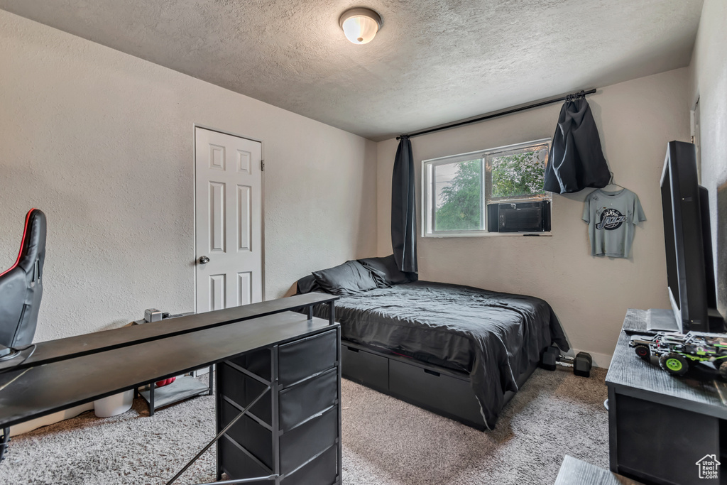 Carpeted bedroom featuring a textured ceiling, cooling unit, and a textured wall