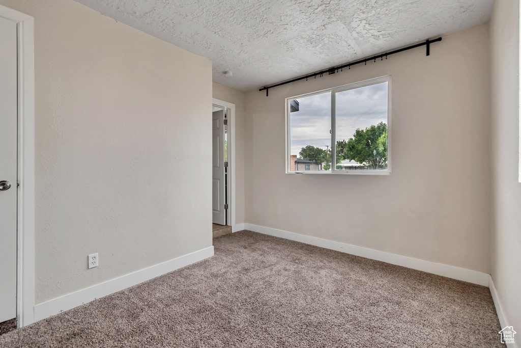 Empty room featuring carpet and a textured ceiling