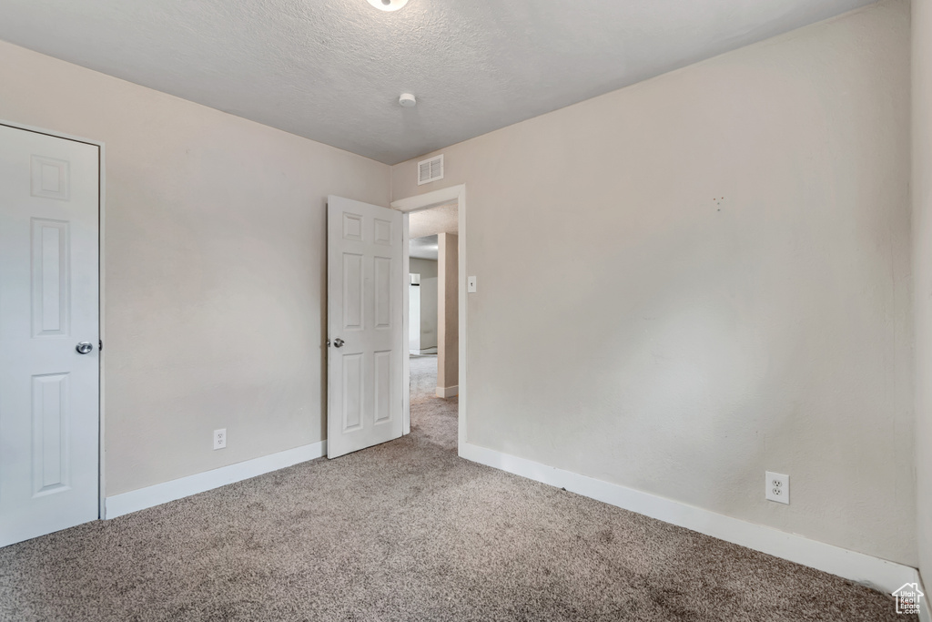 Carpeted empty room featuring baseboards and a textured ceiling