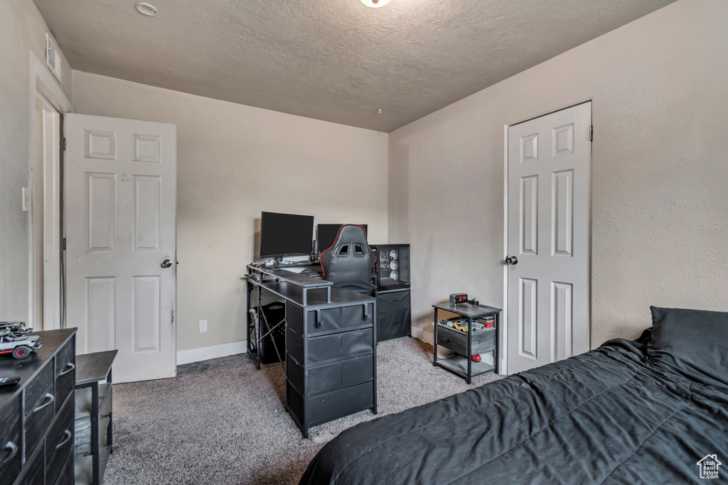 Bedroom with carpet floors, a textured ceiling, and a desk
