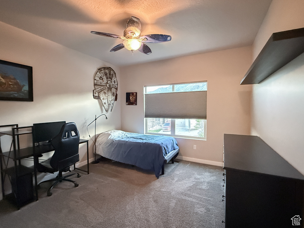Bedroom with dark carpet, a desk, and a ceiling fan