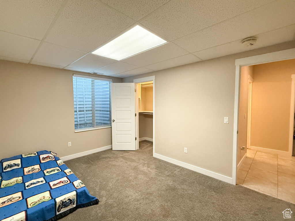Unfurnished bedroom featuring carpet and a drop ceiling