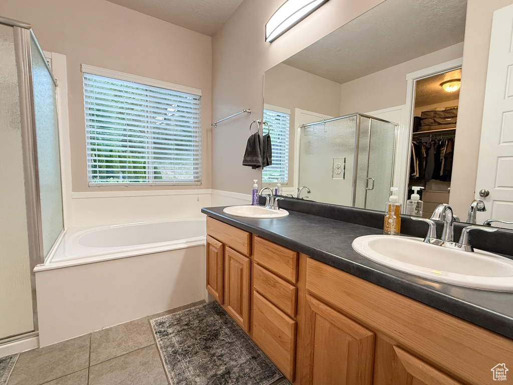 Bathroom with a shower stall, double vanity, a bath, tile patterned floors, and healthy amount of natural light