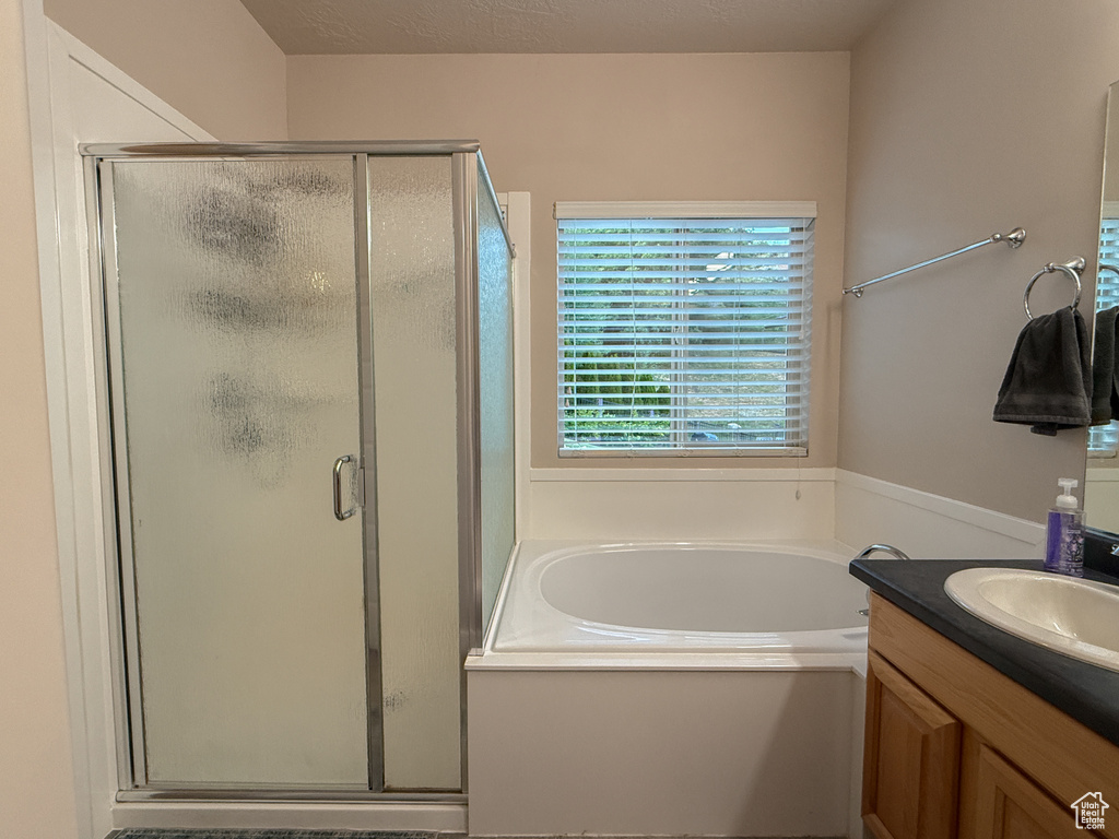 Full bath featuring a bath, a shower stall, and vanity