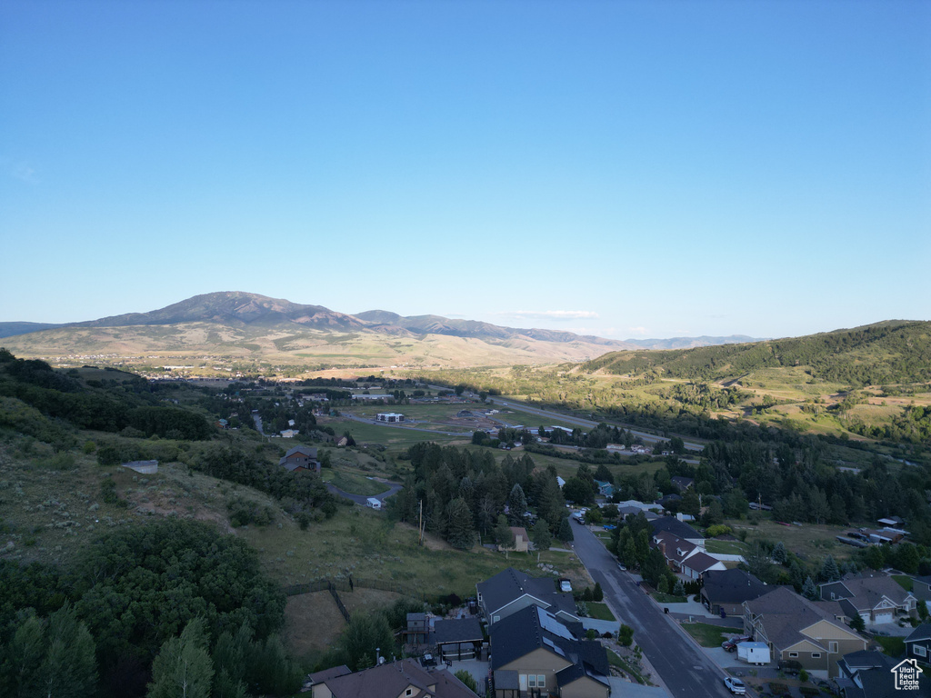 Aerial view of property and surrounding area featuring mountains and nearby suburban area
