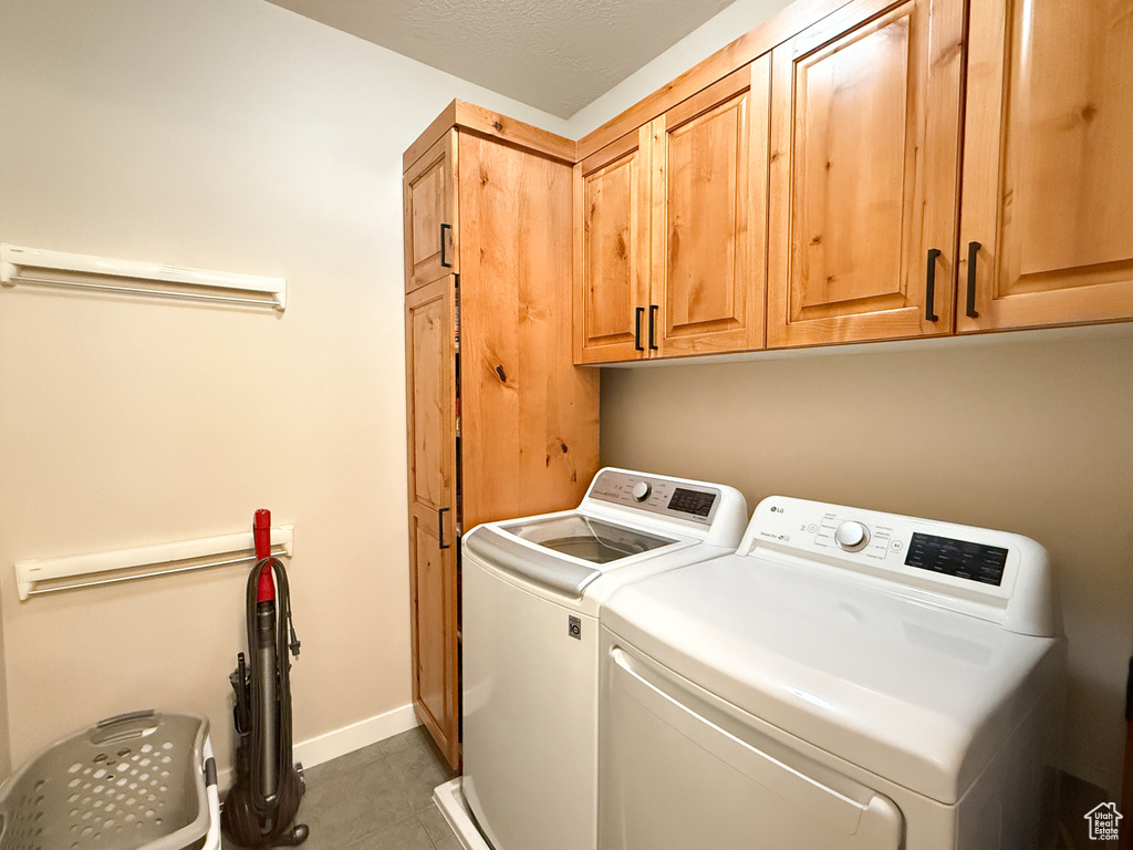 Laundry room with separate washer and dryer, cabinet space, and tile patterned flooring