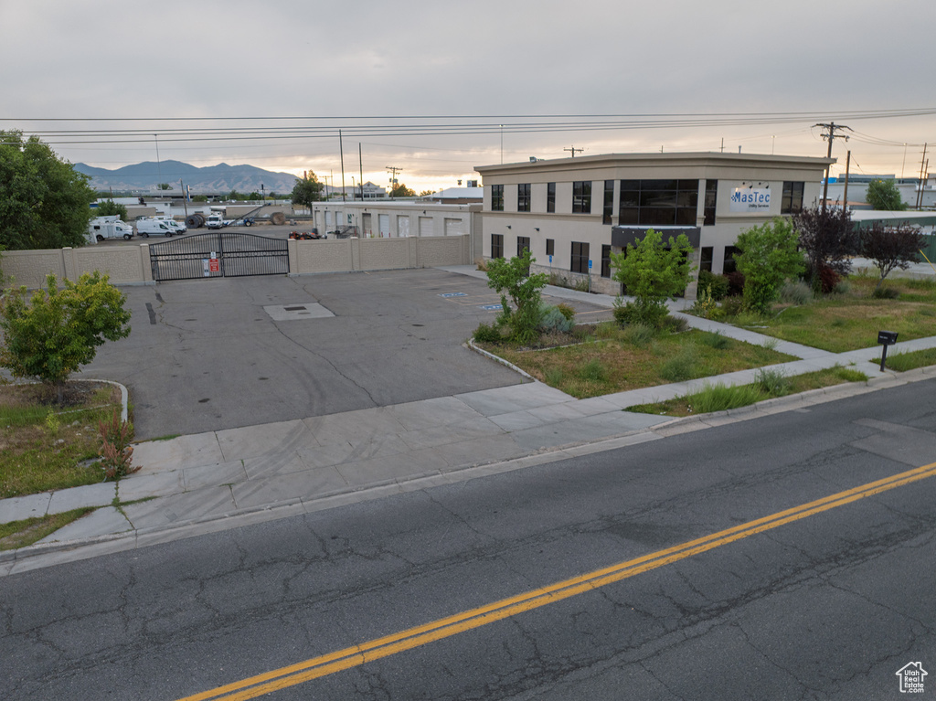 View of asphalt street with a gate, a mountain view, sidewalks, and curbs
