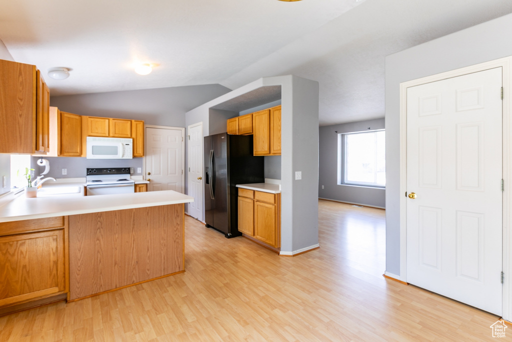 Kitchen featuring white appliances, light wood-type flooring, light countertops, a peninsula, and vaulted ceiling