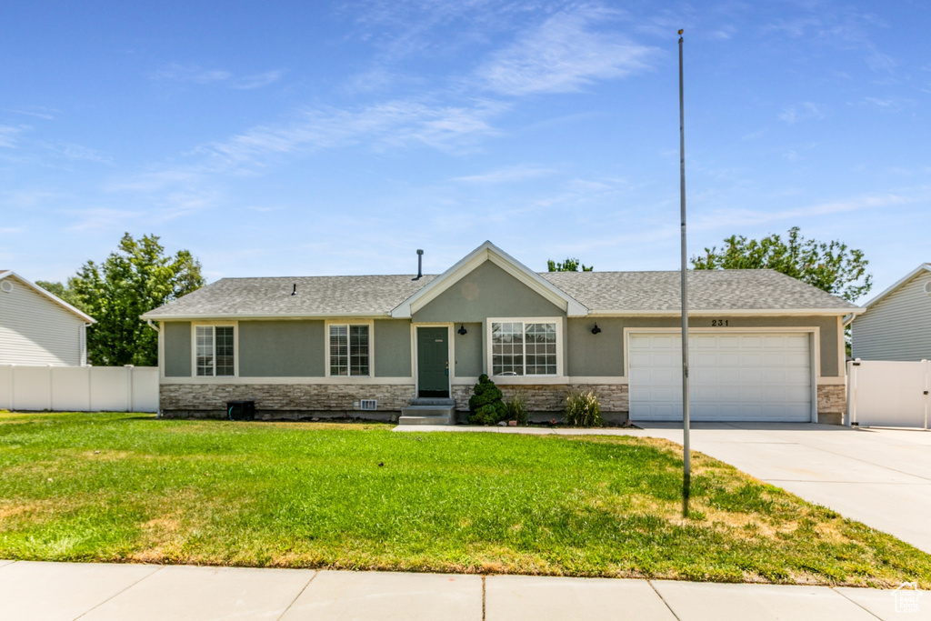 Ranch-style home featuring stucco siding, stone siding, a garage, and concrete driveway