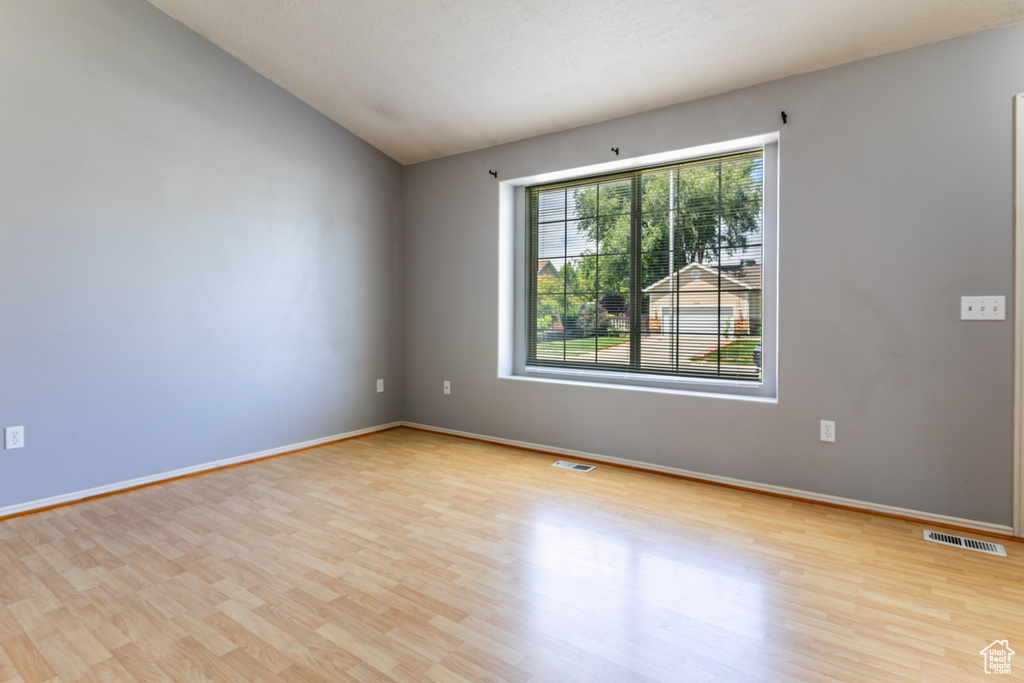 Spare room with wood finished floors and lofted ceiling