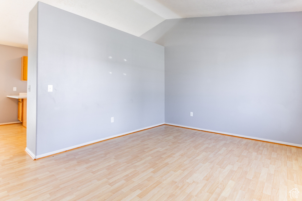 Spare room with light wood-style floors and lofted ceiling