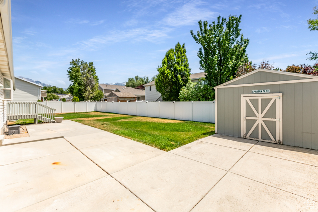 Fenced backyard with a storage unit and a patio
