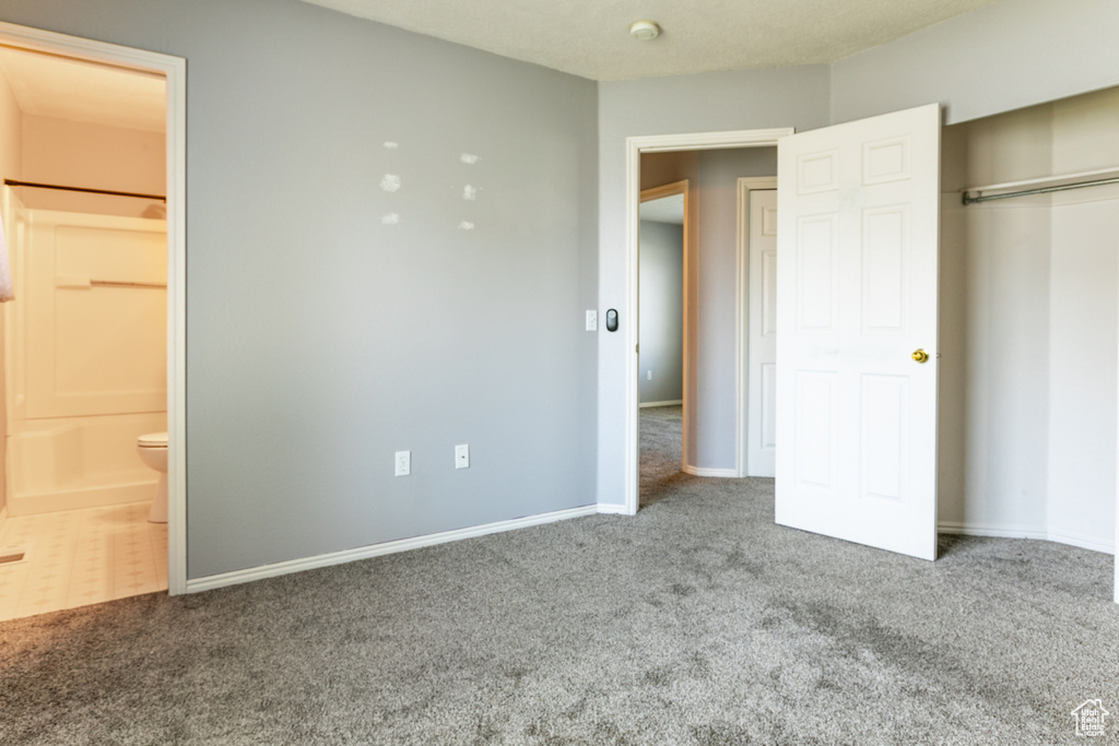 Unfurnished bedroom with carpet, ensuite bathroom, and a closet