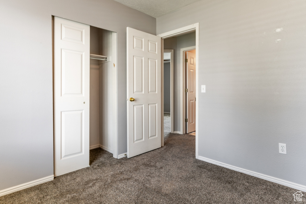 Unfurnished bedroom featuring dark colored carpet and a closet