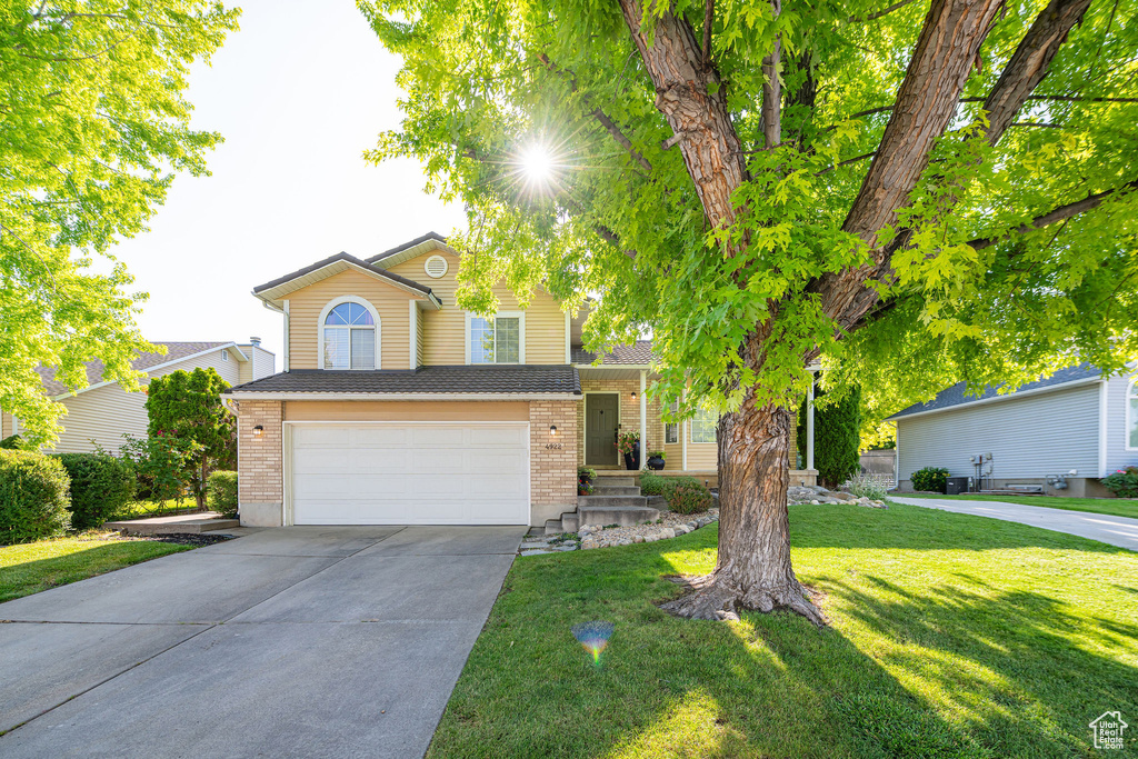 View of front of house featuring brick siding, concrete driveway, a garage, and a front lawn
