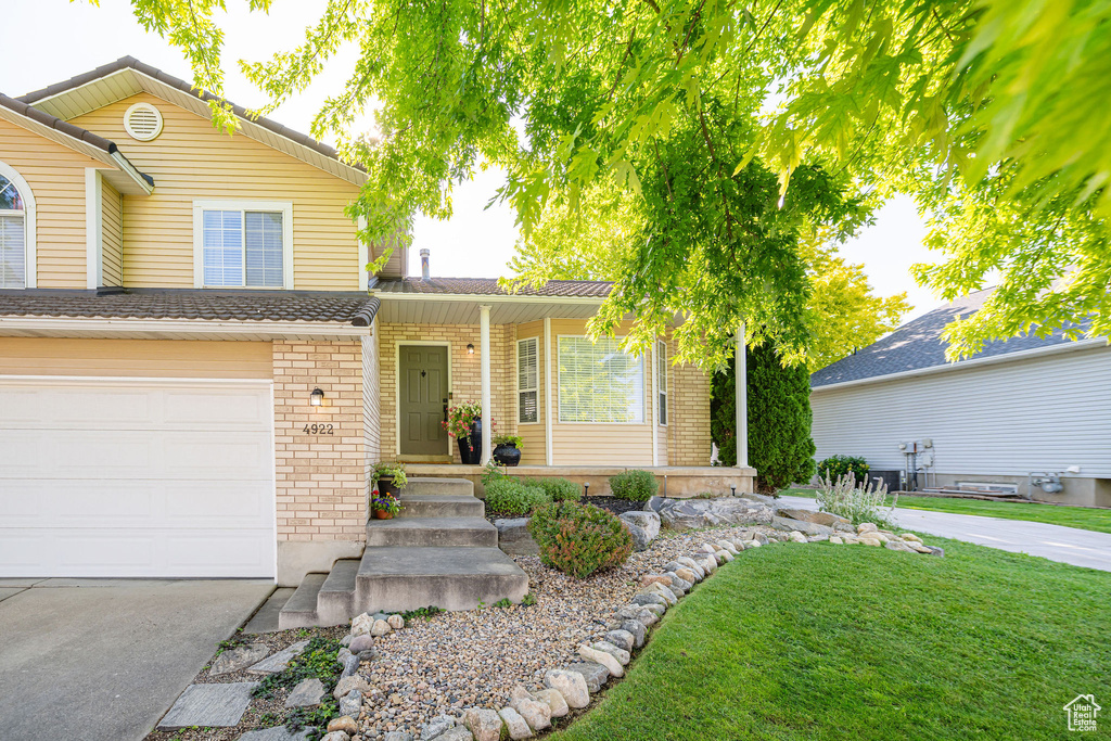 Traditional home with brick siding, concrete driveway, a garage, and a front lawn