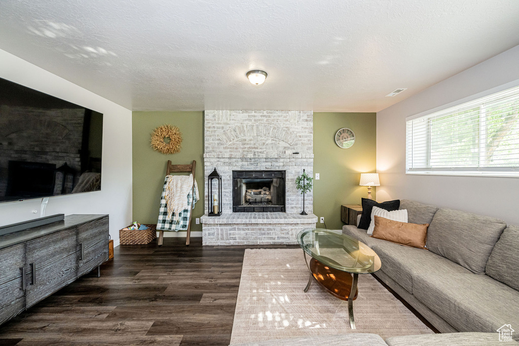 Living room featuring dark wood-style flooring and a fireplace