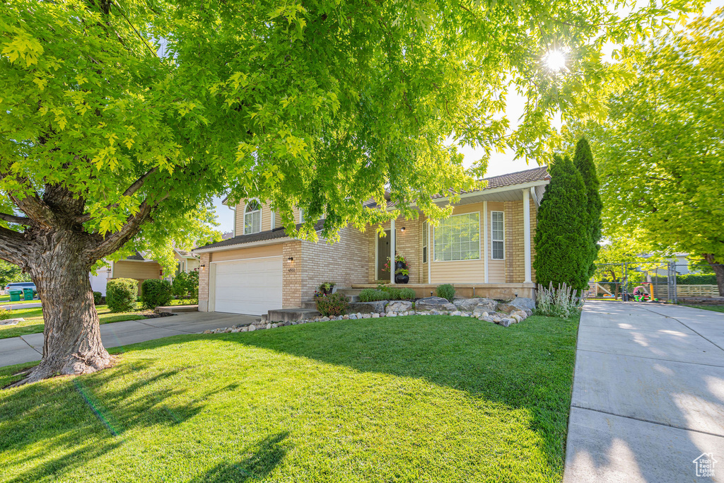 Obstructed view of property with brick siding, driveway, a front yard, and a garage