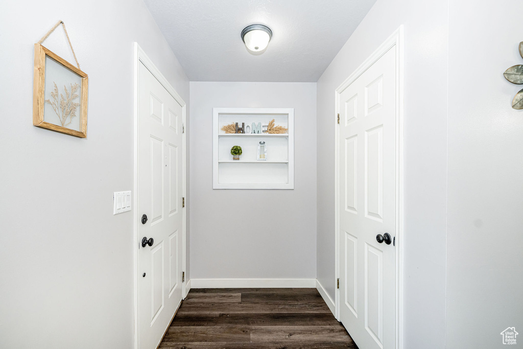 Doorway with dark wood-type flooring and baseboards