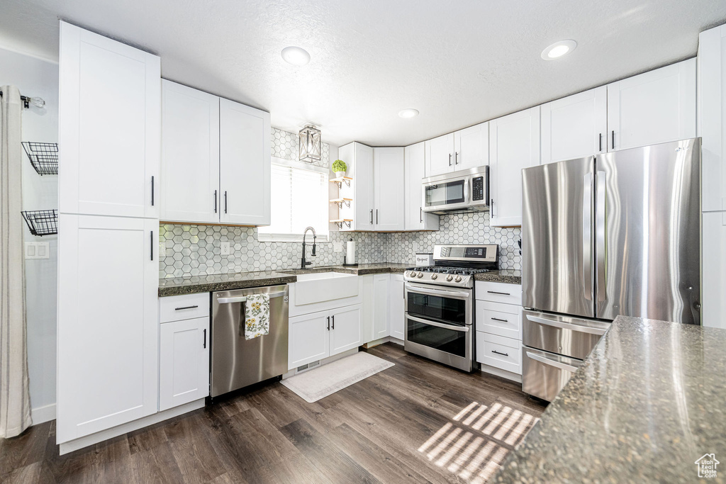 Kitchen featuring appliances with stainless steel finishes, dark countertops, tasteful backsplash, and recessed lighting