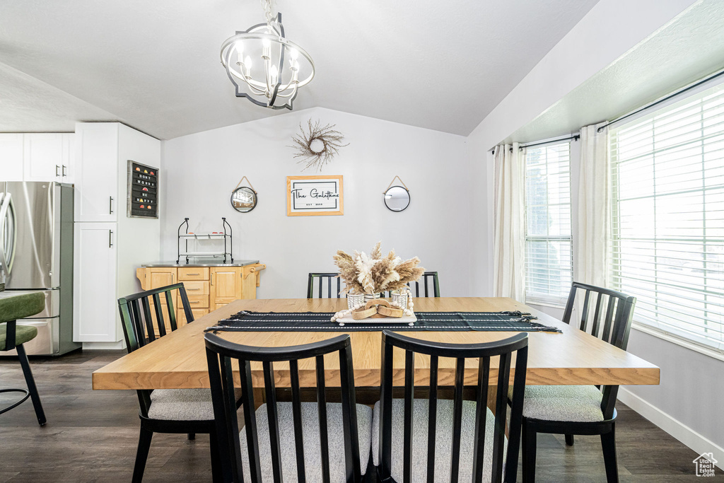 Dining area featuring lofted ceiling, dark wood finished floors, and a chandelier