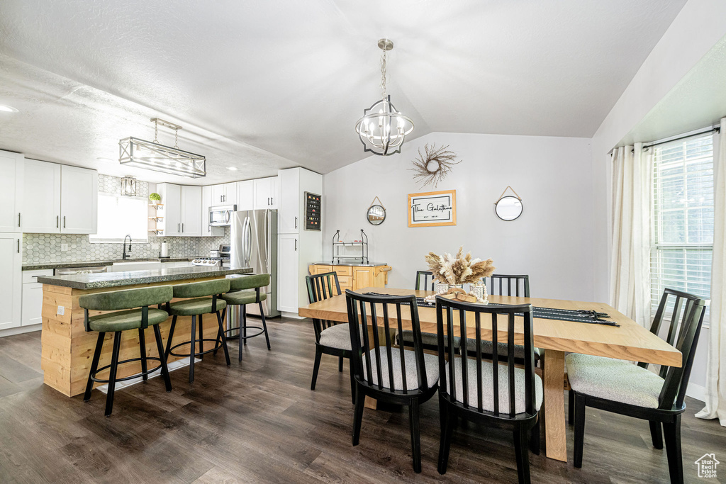 Dining room featuring a chandelier, dark wood finished floors, and vaulted ceiling
