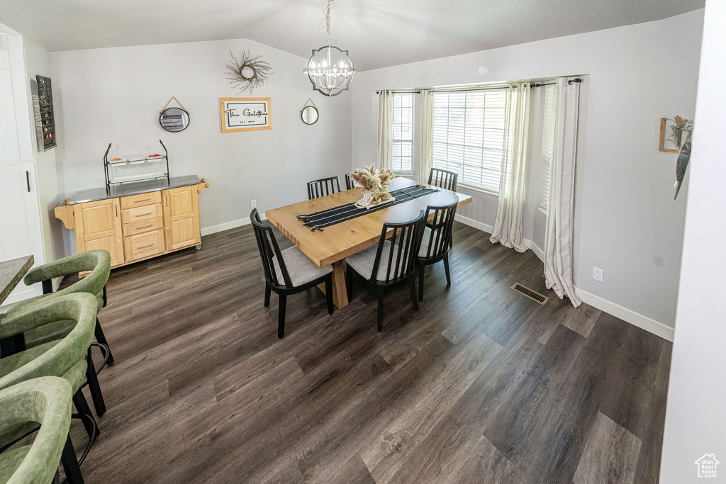 Dining space featuring a chandelier, lofted ceiling, and dark wood finished floors