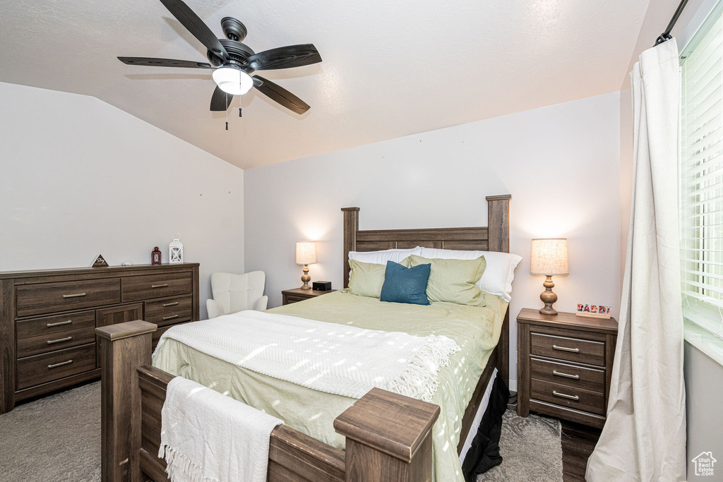 Carpeted bedroom with vaulted ceiling and ceiling fan