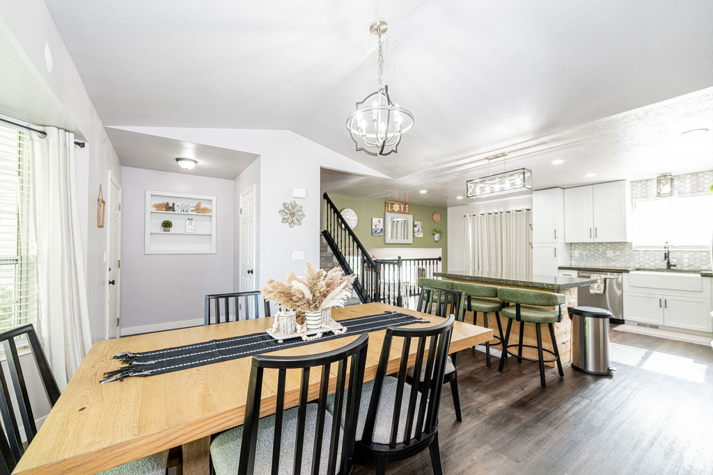 Dining room featuring a chandelier, vaulted ceiling, wood finished floors, and plenty of natural light