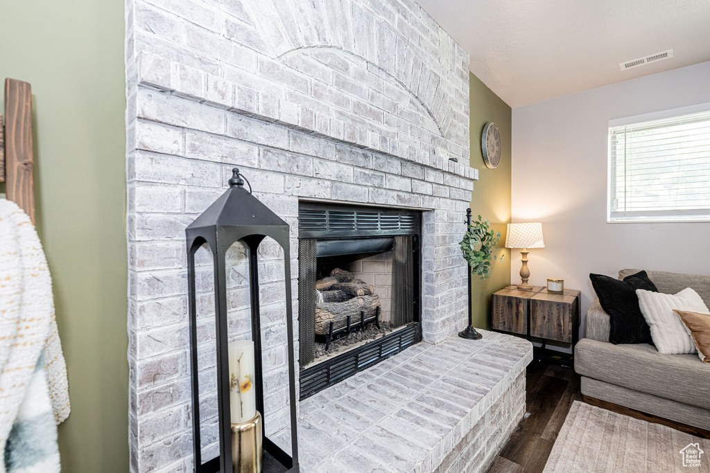 Living area featuring dark wood-style floors and a brick fireplace