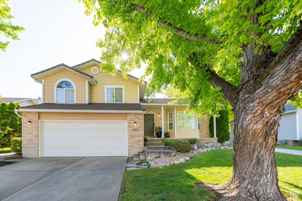 View of front of home featuring concrete driveway, brick siding, a garage, and a front lawn