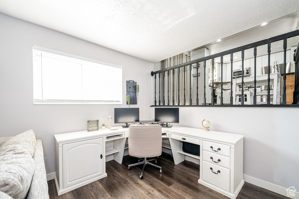 Office space with built in study area, dark wood-type flooring, a textured ceiling, and recessed lighting