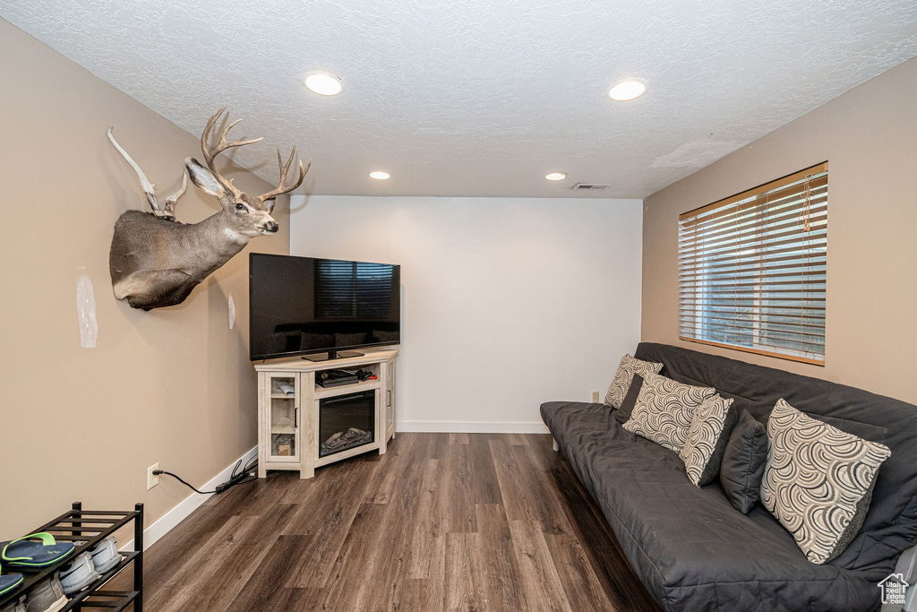 Living area featuring dark wood-style flooring, recessed lighting, and a textured ceiling