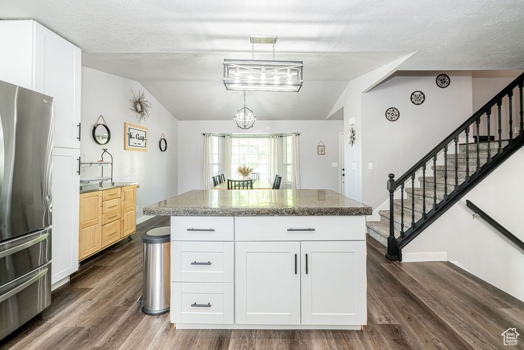 Kitchen with freestanding refrigerator, lofted ceiling, dark wood-type flooring, a chandelier, and white cabinetry