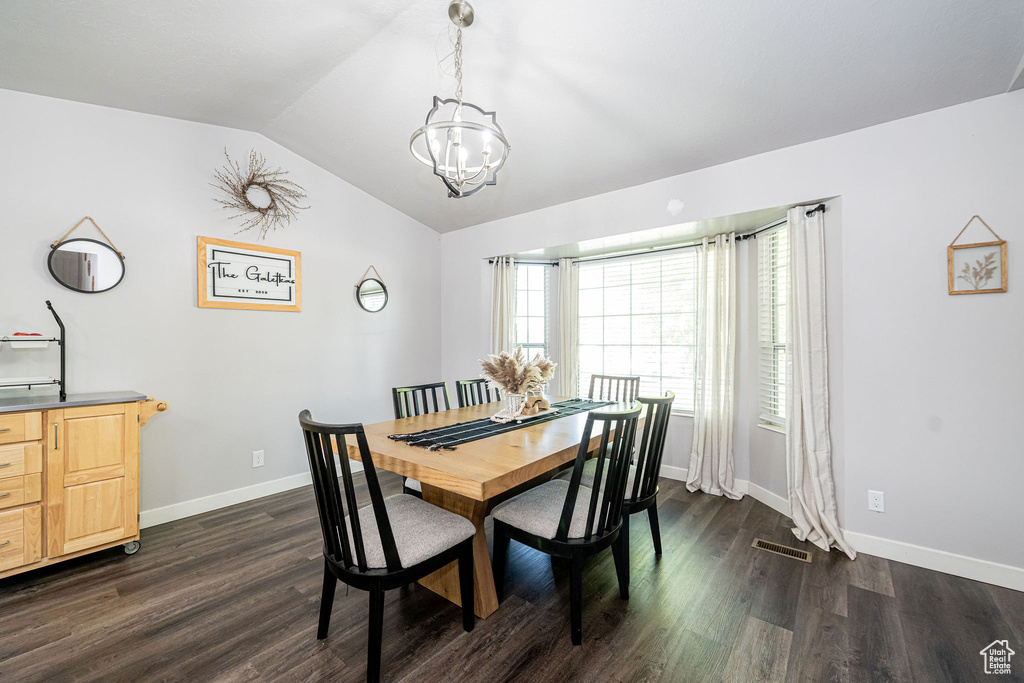 Dining room with a chandelier, vaulted ceiling, and dark wood-style floors