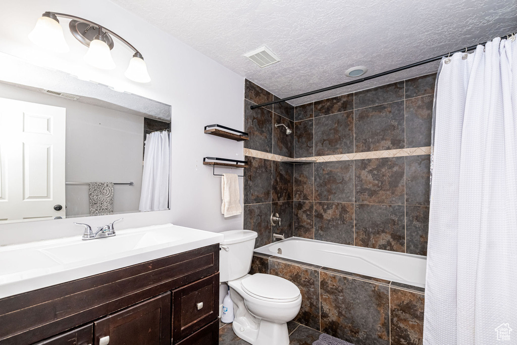 Full bath with tiled shower / bath, vanity, and a textured ceiling