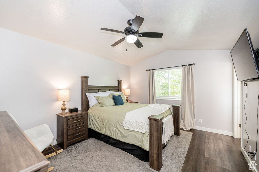 Bedroom featuring dark wood-type flooring, lofted ceiling, and a ceiling fan