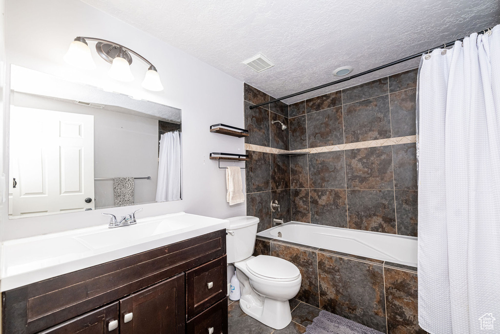 Full bathroom featuring tiled shower / bath, vanity, tile patterned flooring, and a textured ceiling