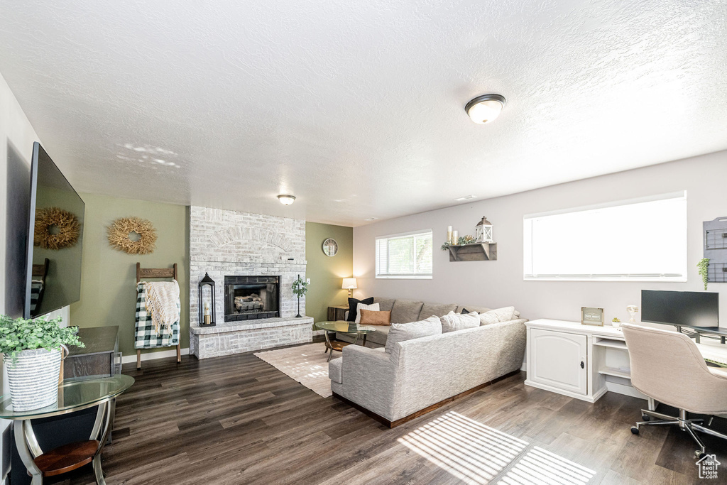 Living room featuring wood finished floors, a fireplace, a textured ceiling, and an office area