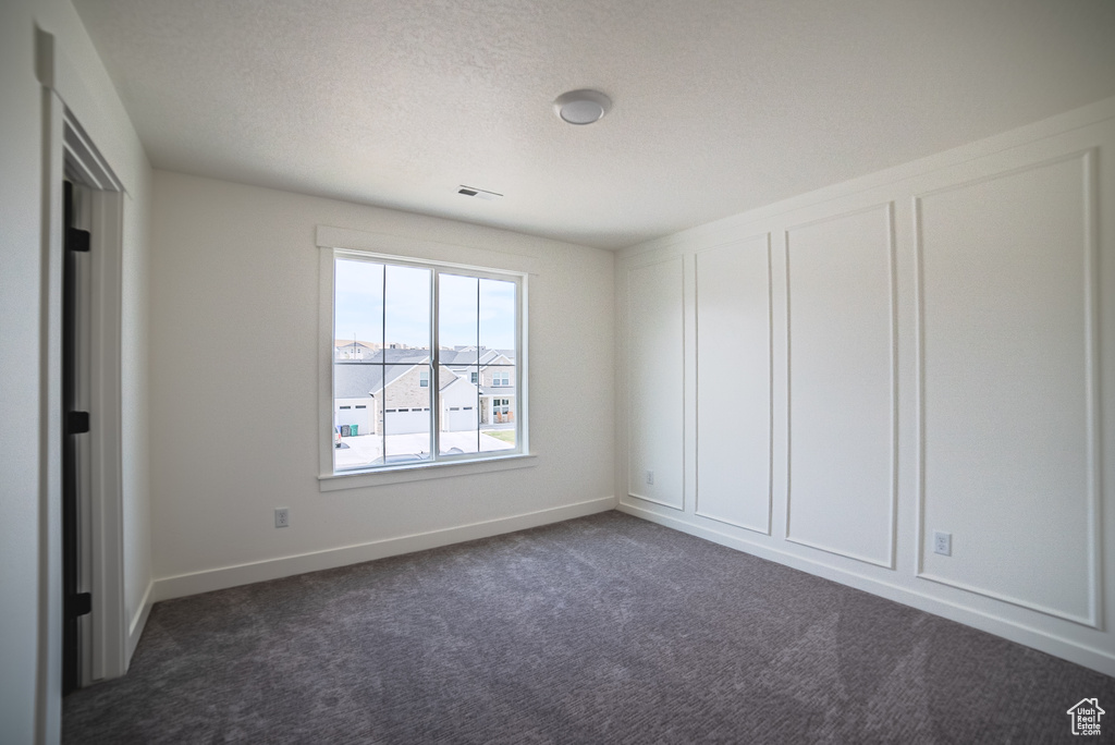 Spare room with dark colored carpet and a textured ceiling