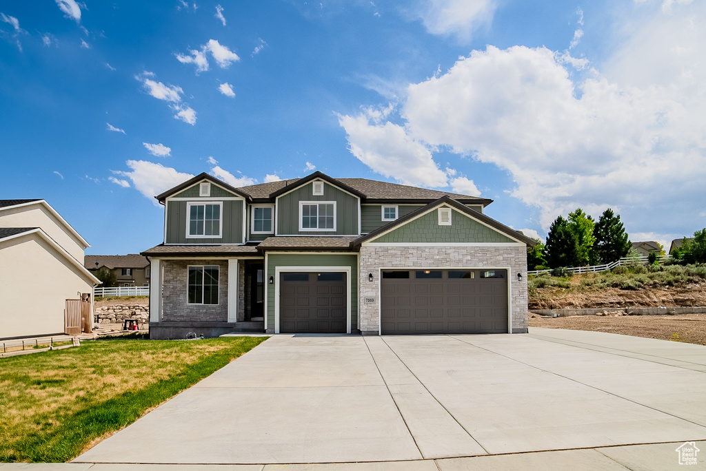Craftsman inspired home featuring concrete driveway, an attached garage, stone siding, and a shingled roof