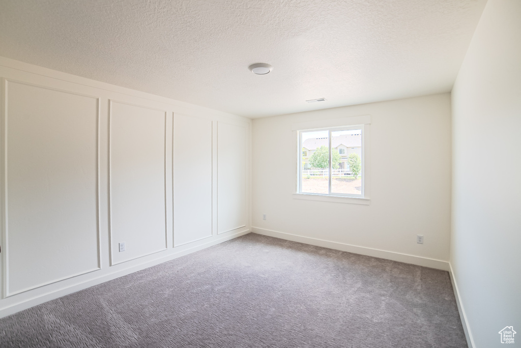 Unfurnished room with carpet and a textured ceiling