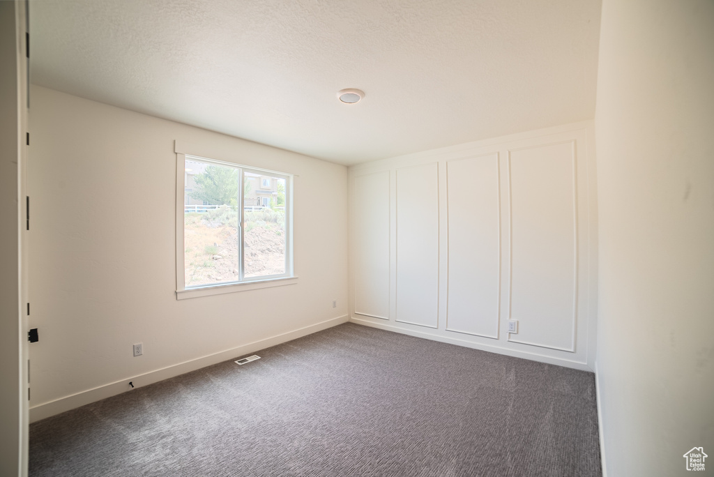Empty room with dark carpet and baseboards