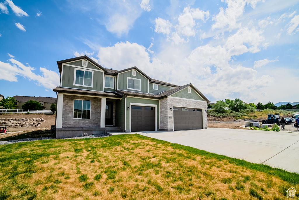 Craftsman inspired home featuring concrete driveway, board and batten siding, stone siding, covered porch, and an attached garage