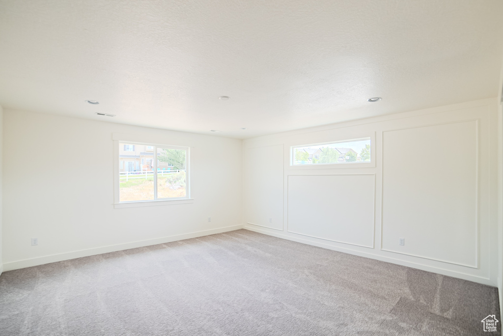 Empty room with light carpet and recessed lighting