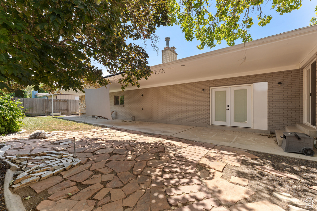 Back of property with brick siding, a chimney, a patio, and french doors