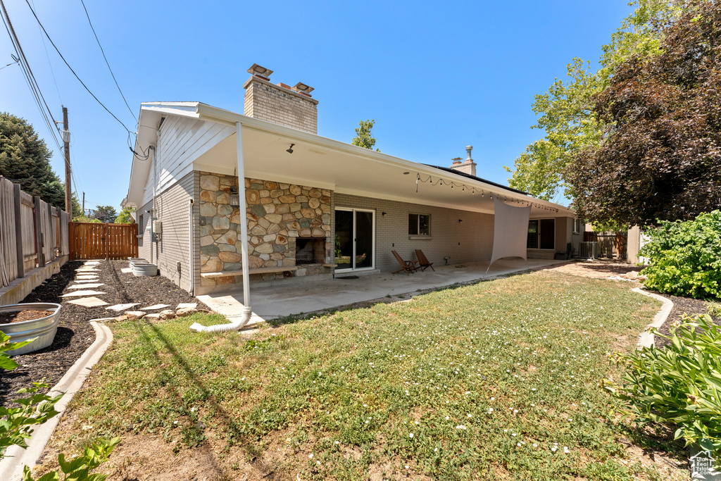 Back of house featuring a chimney, a fenced backyard, a patio, and stone siding