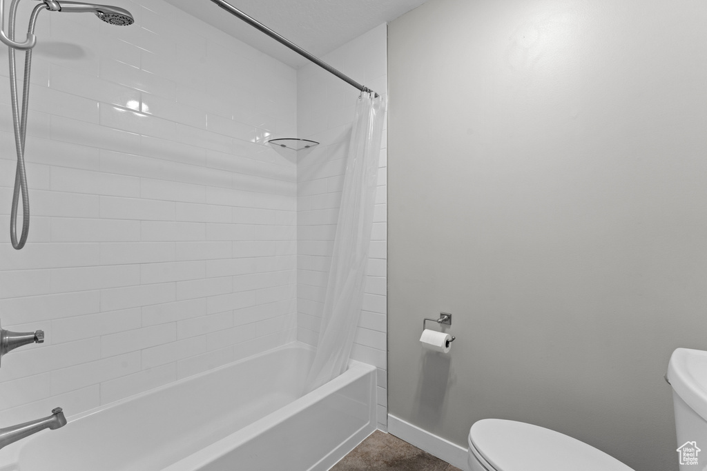 Bathroom featuring toilet and shower / bathtub combination with curtain